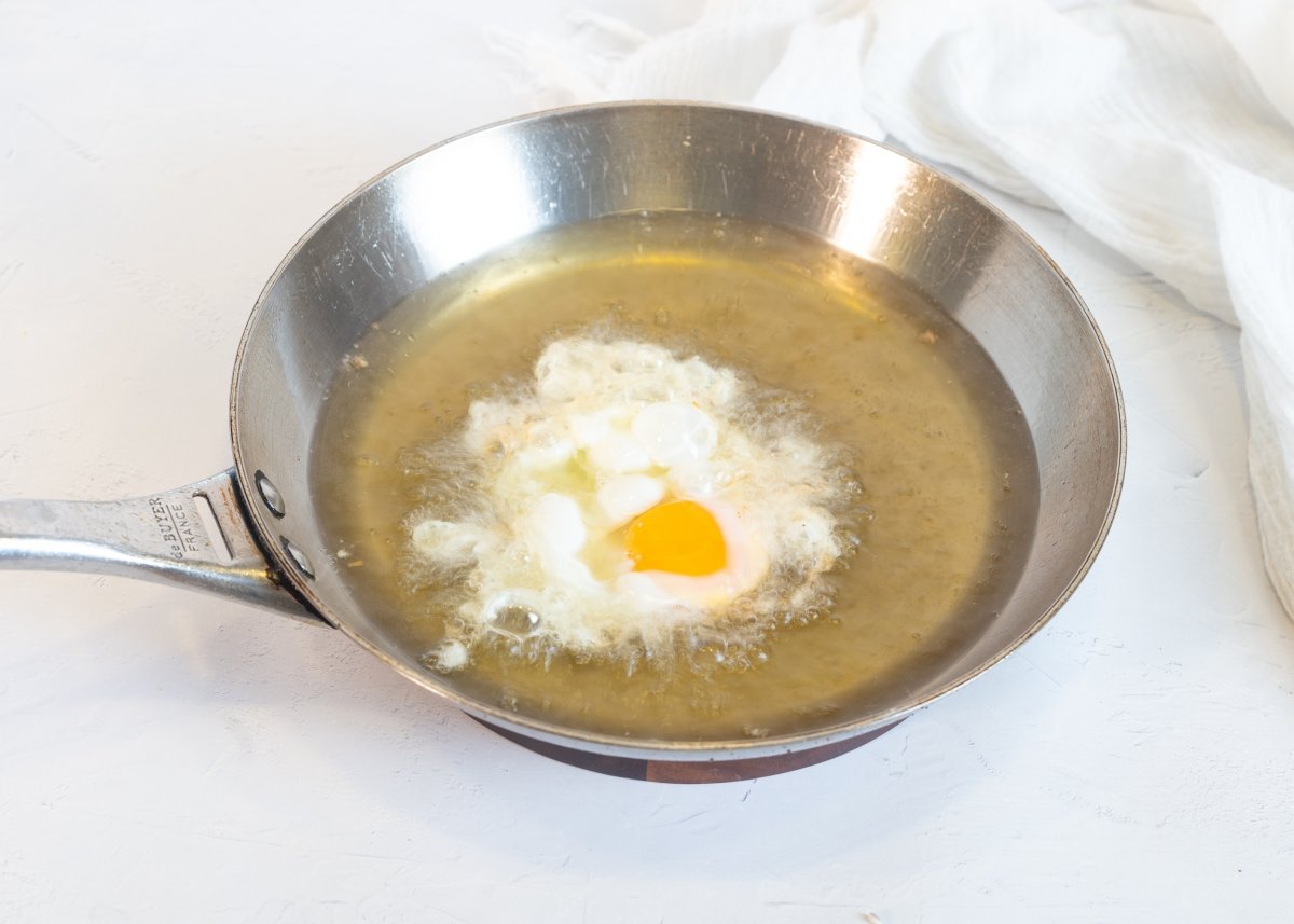 Friendo el huevo para hacer huevos rotos con gulas