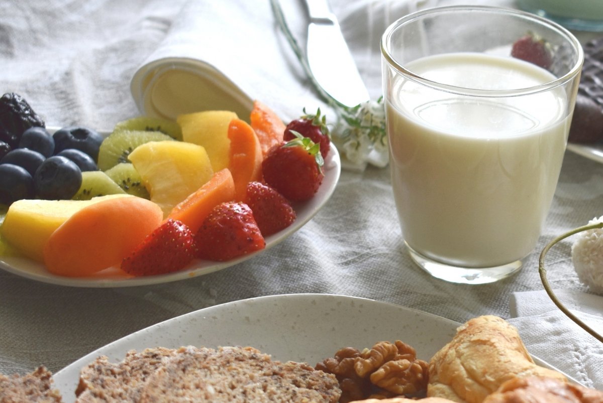 Fruta junto a un vaso de leche y algunos frutos secos y alimentos a base de harina