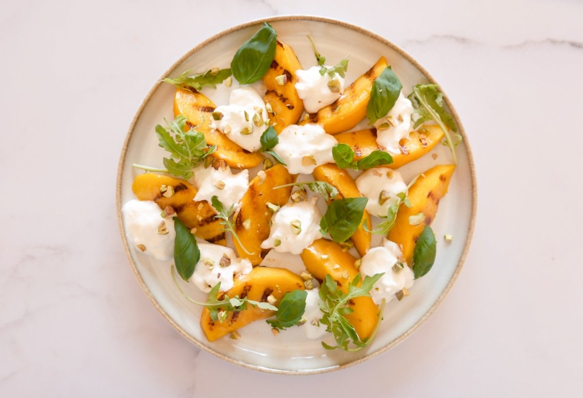 Gajos de melocotón con burrata, albahaca, rúcula y pistachos