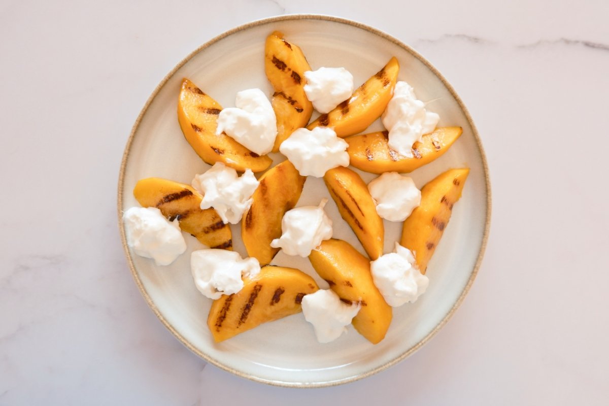 Gajos de melocotón y burrata dispuestos en un plato