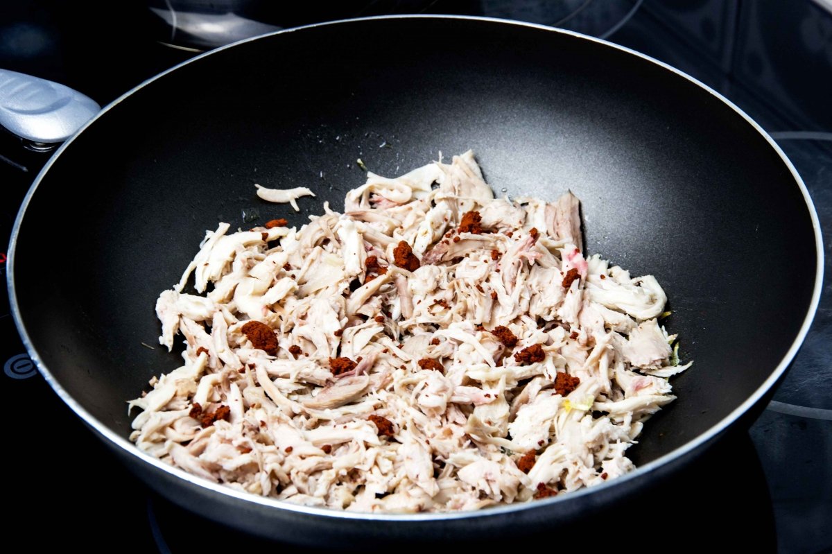 Guisar el pollo en wok con pasta de achiote y caldo para hacer las quesadillas de pollo
