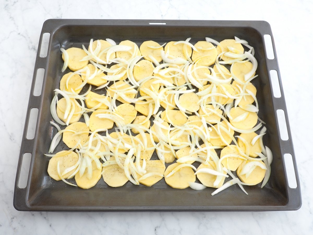 Hacer una cama de patatas y cebolla en la bandeja del horno