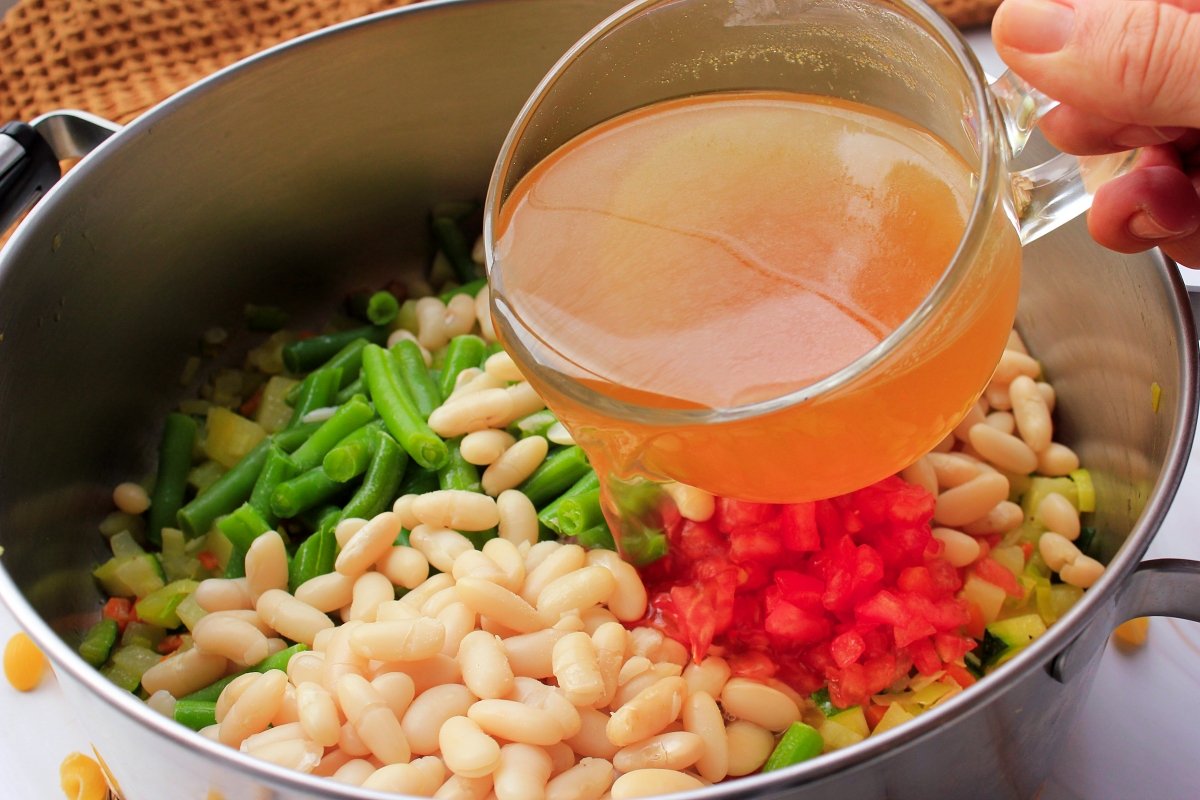 Incorporación del caldo vegetal para hacer la sopa minestrone