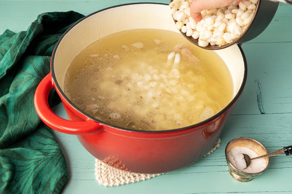 Incorporar el mote de maíz para el pozole rojo y cocinar 10 minutos