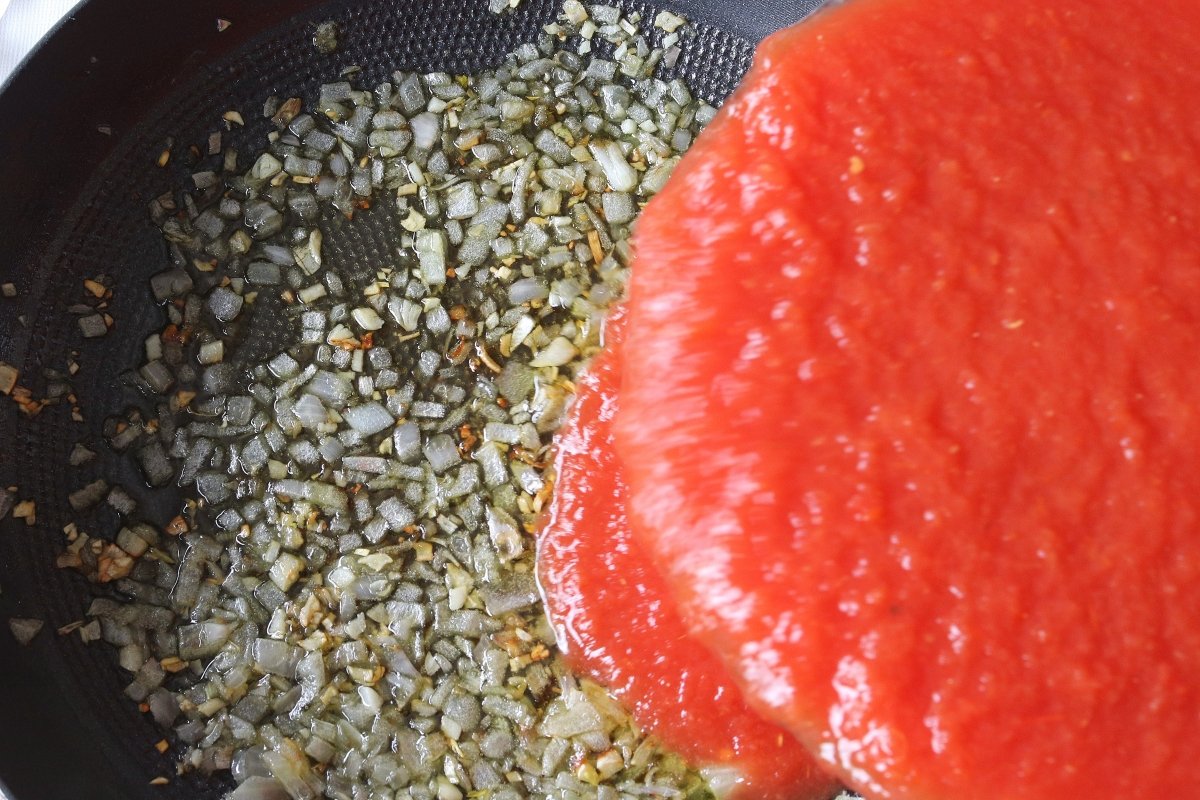 Incorporar el puré de tomate y cocinar a fuego suave durante 45 minutos