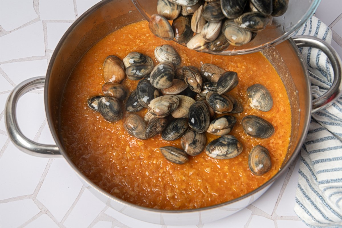 Incorporar el vino blanco, la salsa de tomate y un poco de perejil