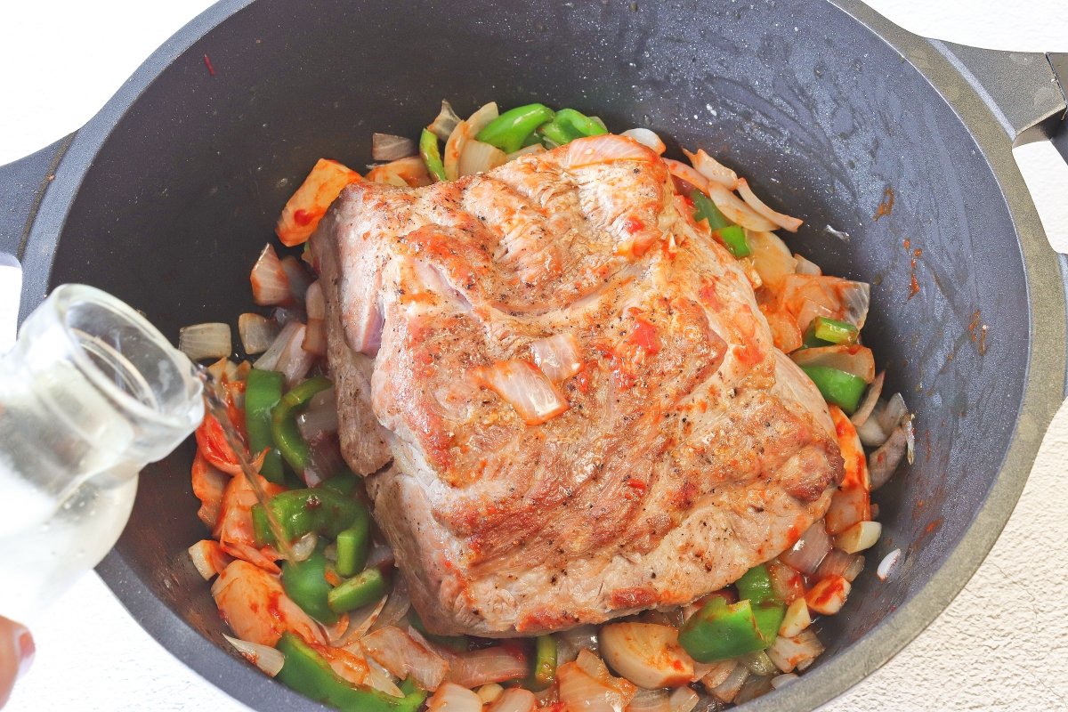 Incorporar la cabezada de cerdo a las verduras para hacerla en salsa