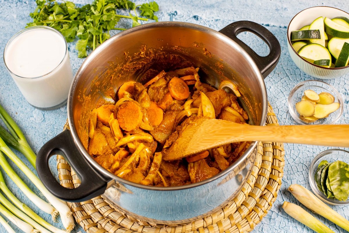 Incorporar la cebolla y zanahoria al pollo al curry amarillo