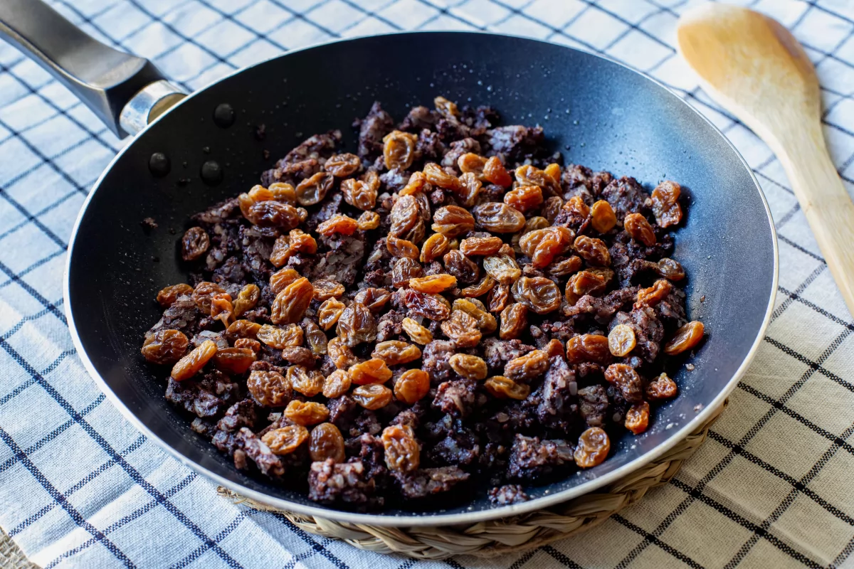 Incorporar las pasas a la morcilla en la sartén para hacer el revuelto *
