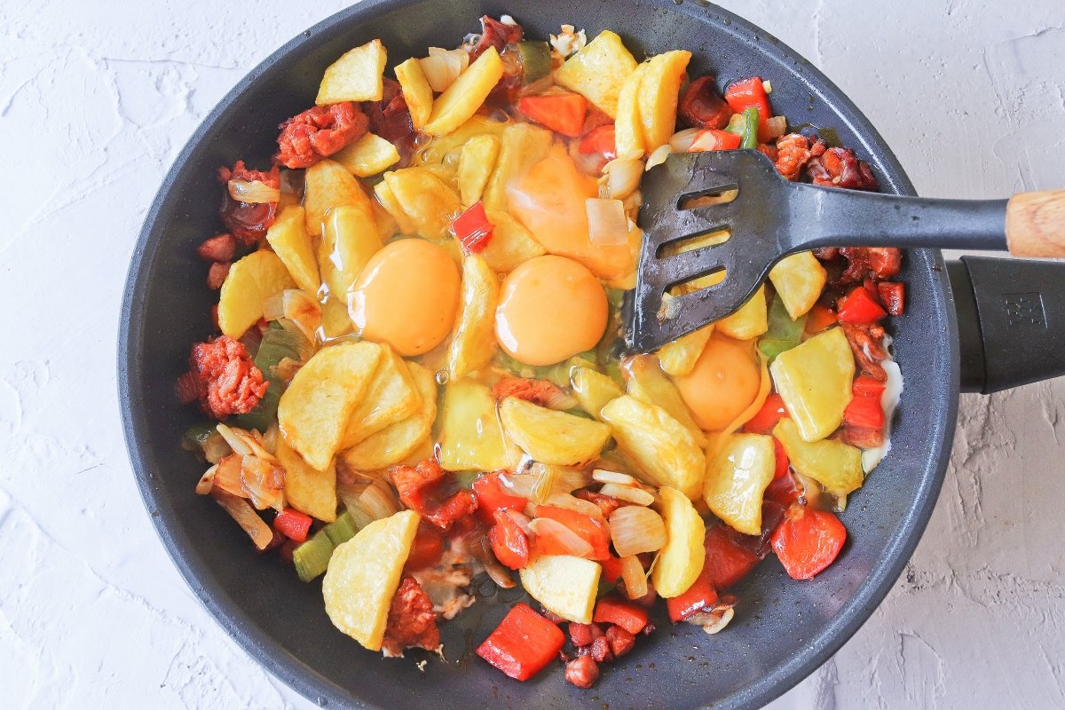 Incorporar las patatas fritas y los huevos a la sartén para el revuelto campero