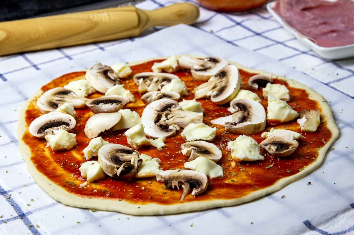 Incorporar los champiñones a la pizza romana