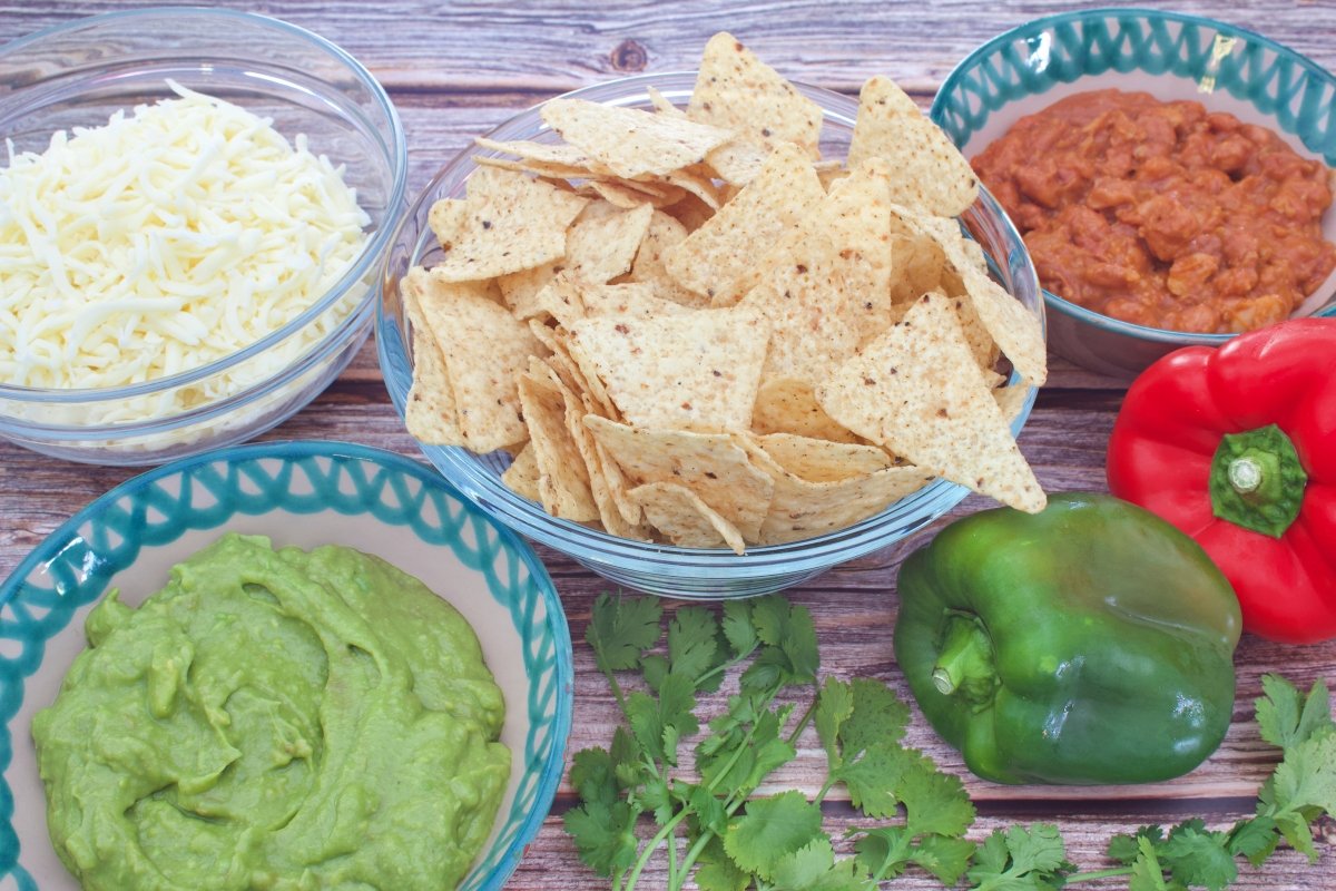 Ingredientes de los nachos mexicanos con queso, guacamole y chili con carne
