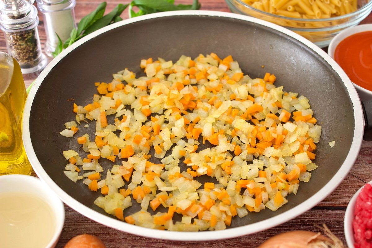 La cebolla y la zanahoria de los macarrones a la boloñesa con carne picada en una sartén