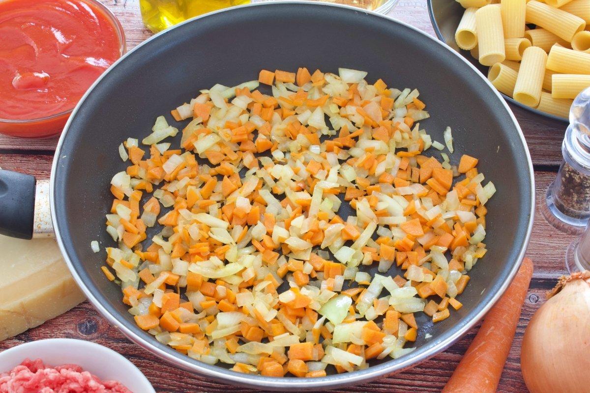 La cebolla y la zanahoria de los rigatoni con salsa boloñesa picadas y en la sartén
