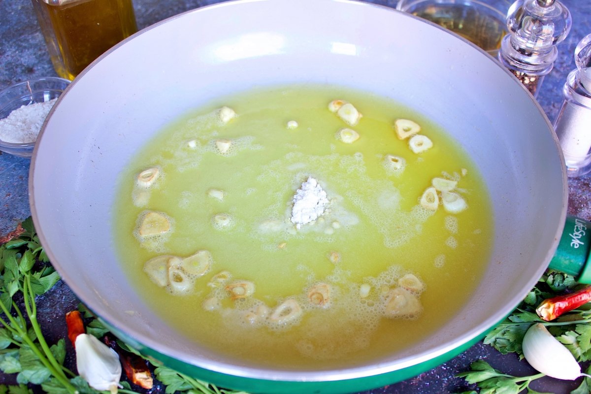 La harina de las cocochas de bacalao en salsa verde añadida en la sartén