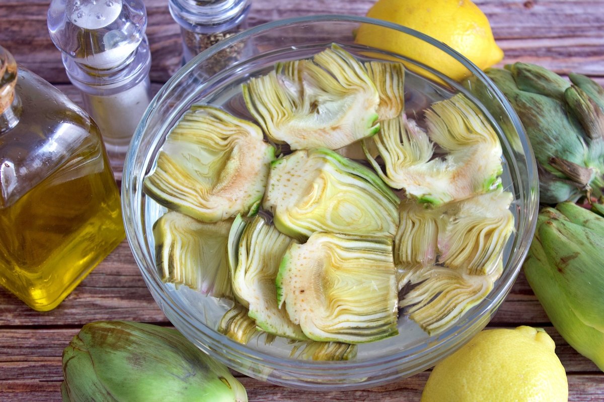 Las alcachofas de las alcachofas fritas crujientes en un bol con agua y zumo de limón