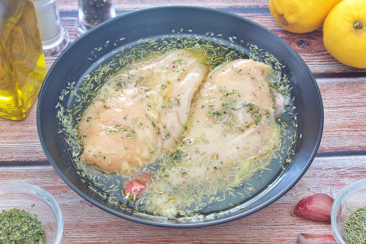 Las pechugas de pollo al horno marinando en un bol con el resto de ingredientes