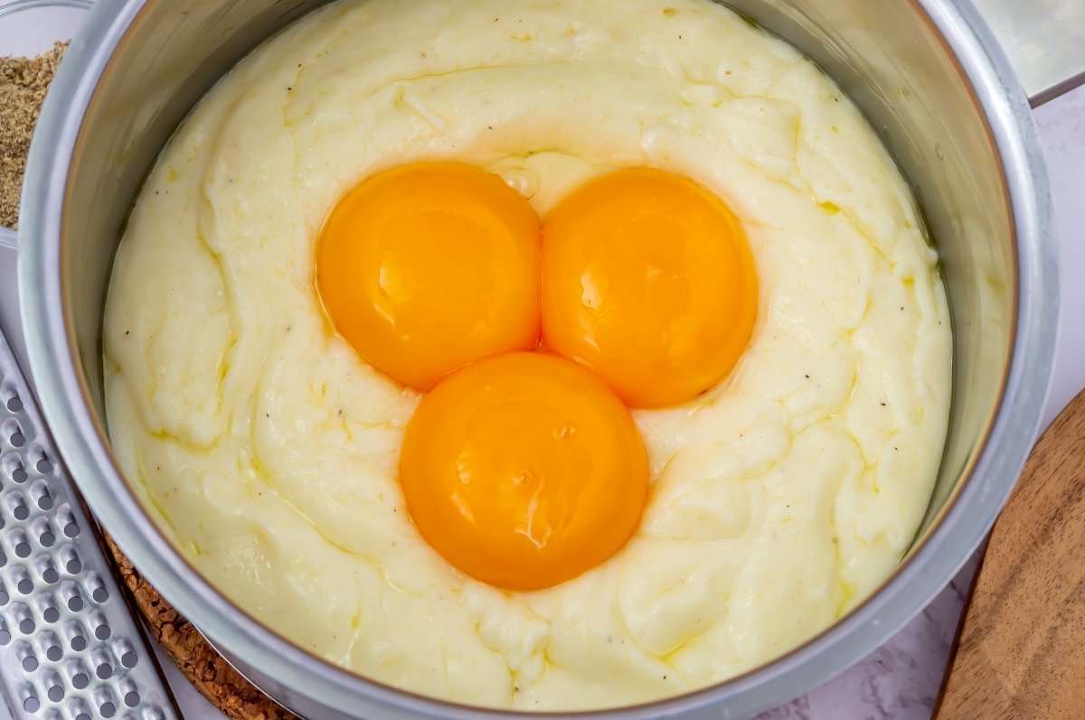 Las yemas de huevo se echan sobre la base de bechamel y queso