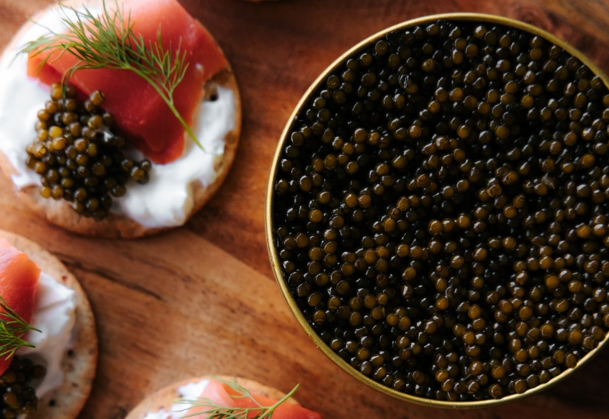 Lata de caviar y huevas sobre una receta de blinis