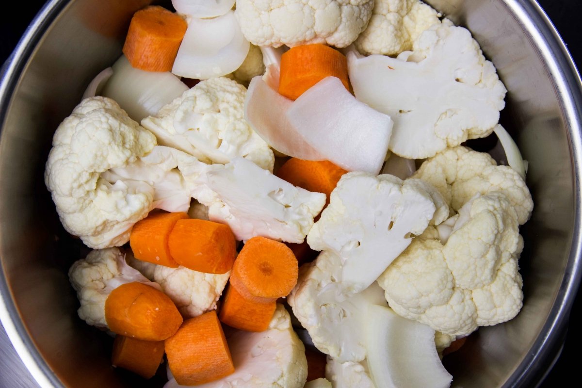 Lavar, trocear y rehogar las verduras en la olla para hacer la crema de coliflor y zanahoria