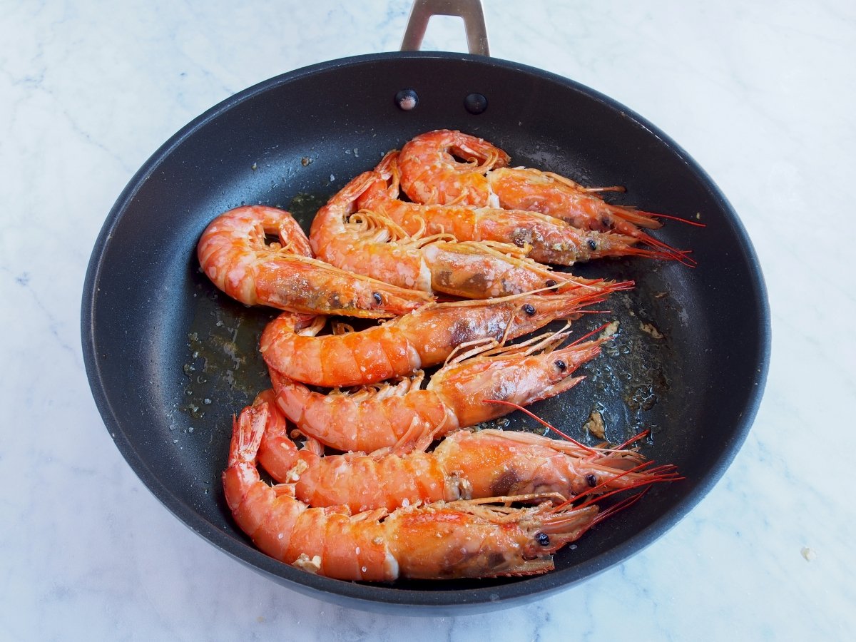 We turn the prawns, add a little olive oil and cook for 1 minute