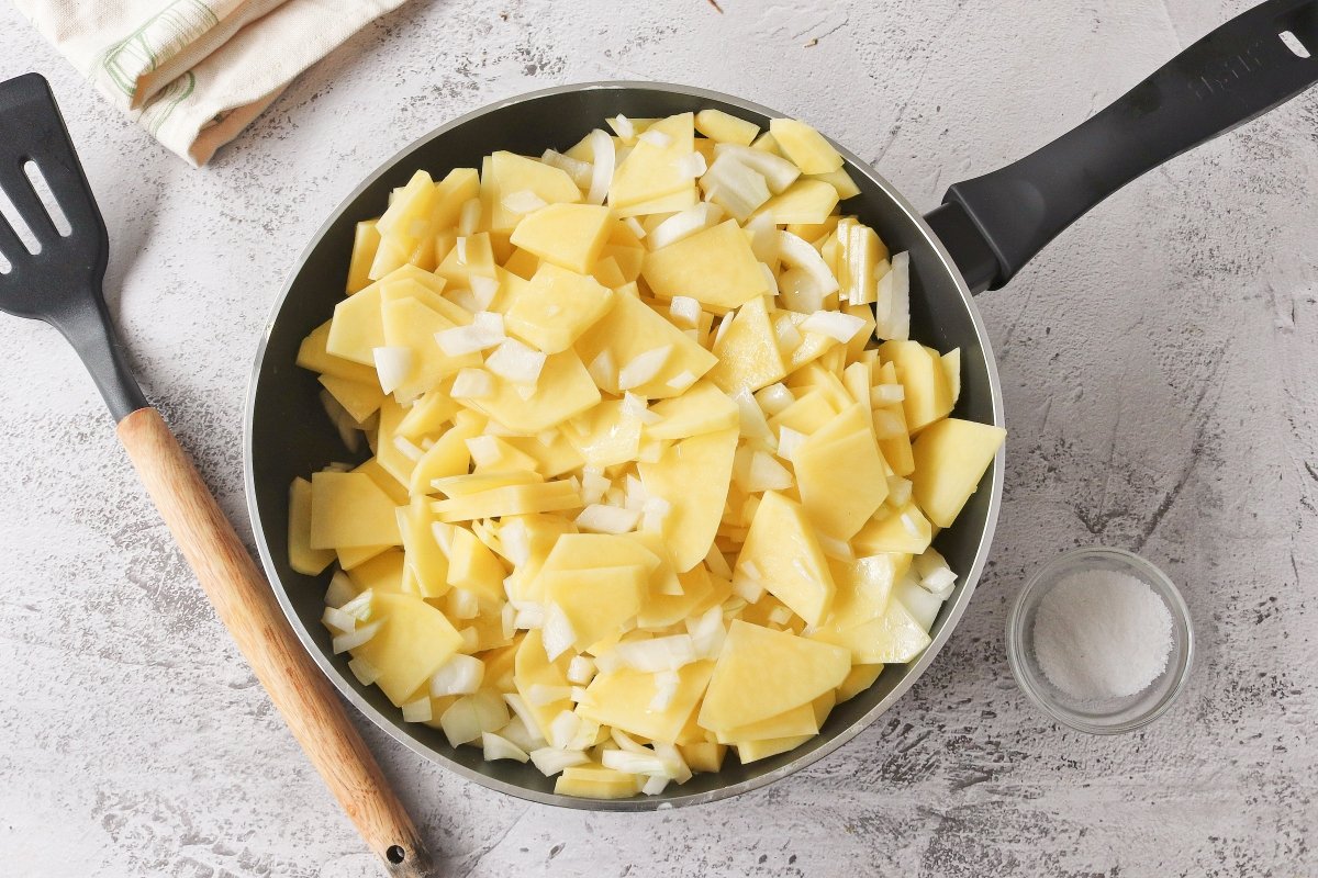 Llevar a una sartén las patatas y la cebolla para hacer la tortilla rellena de jamón y queso