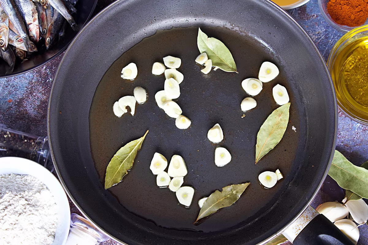 Los ajos y el laurel en la sartén de los boquerones en escabeche