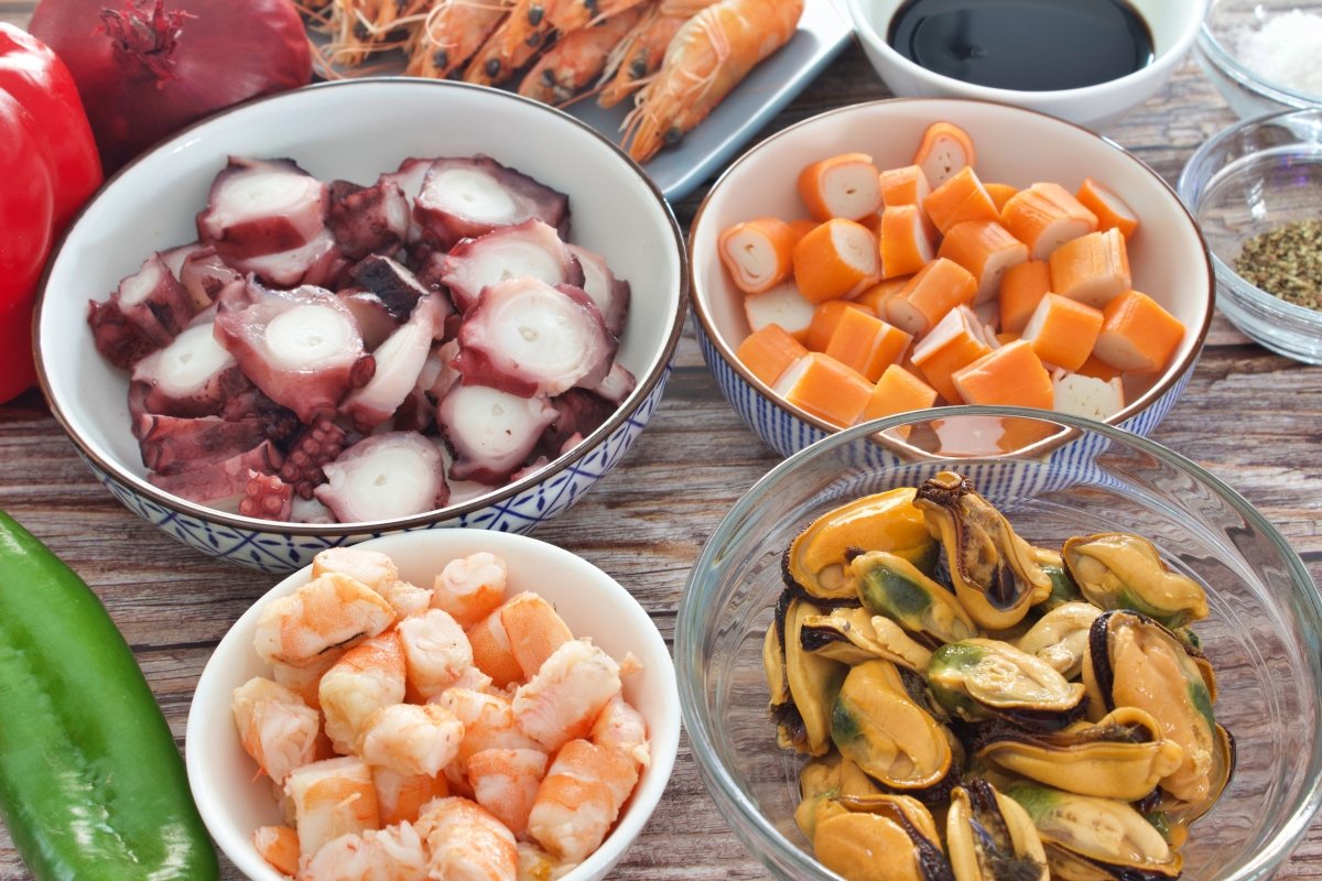 Los palitos de cangrejo, las gambas, el pulpo y los mejillones del salpicón de marisco cortados y pr