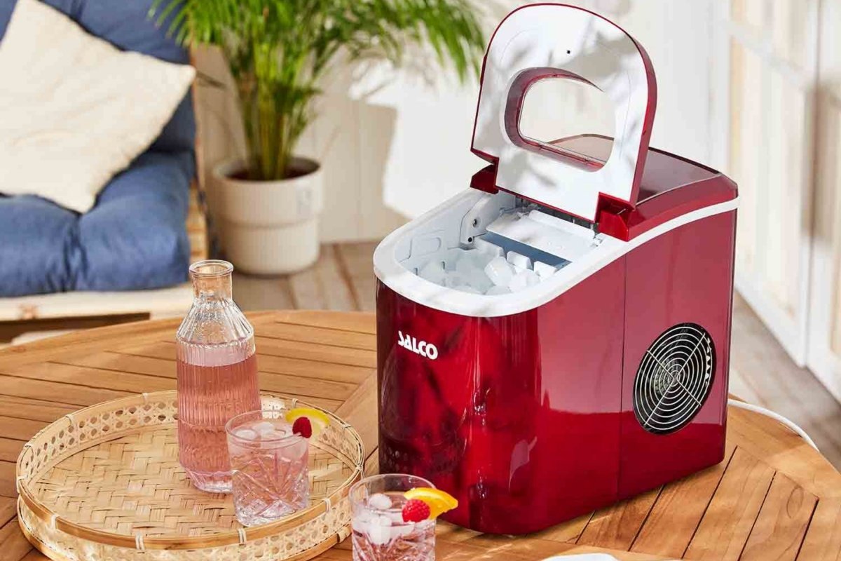 Máquina para hacer hielos de Lidl en una cocina, con la cubierta abierta, hielo en el interior y rodeada de vasos con bebidas fresquitas