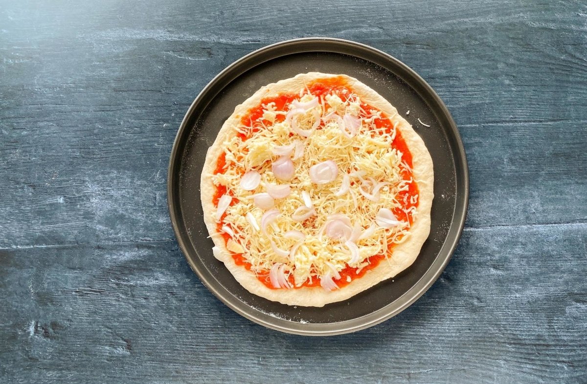 Masa de pizza casera con quesos y cebolla laminada