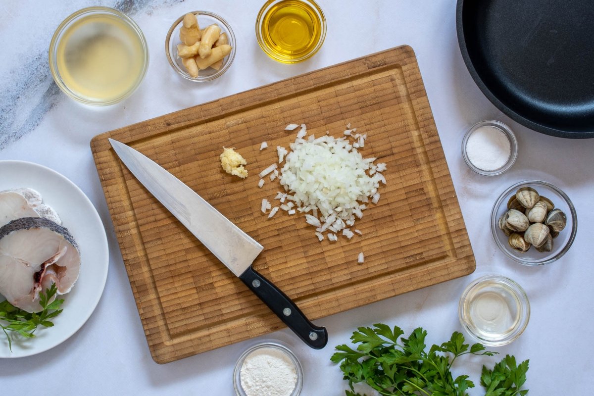 Picar el ajo y la cebolla para la merluza en salsa verde