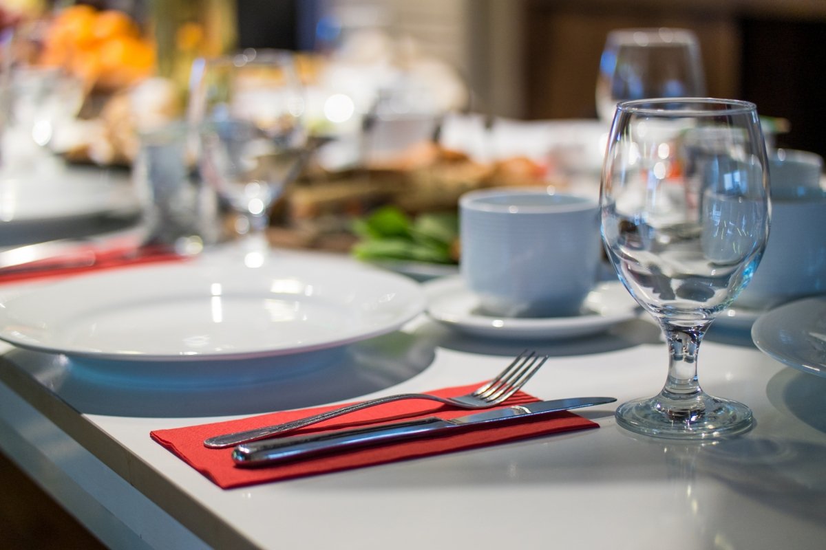 Mesa con comida, platos, copas y una servilleta roja sobre la que hay unos cubiertos