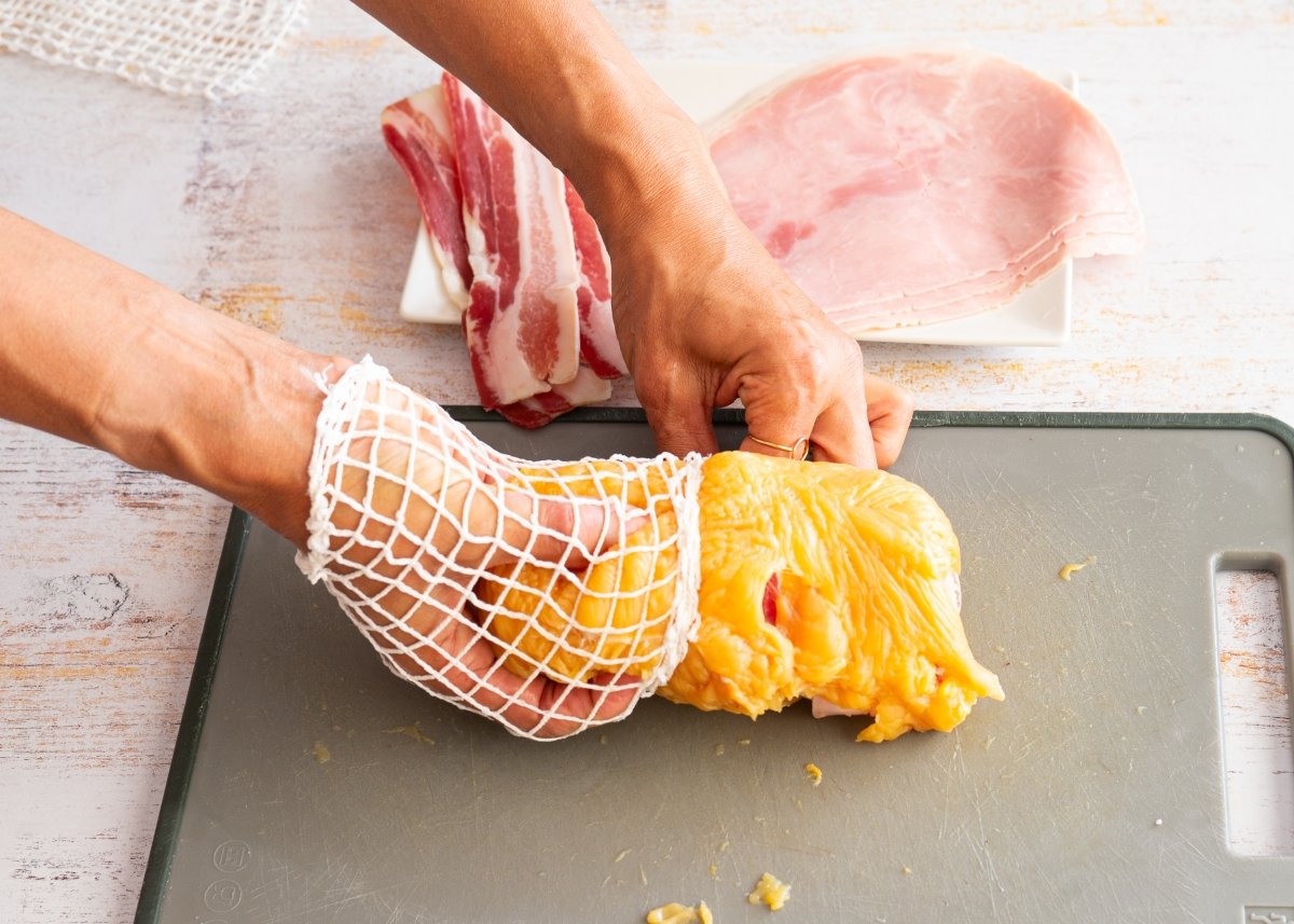 Metiendo el roti de pollo en una malla para carne