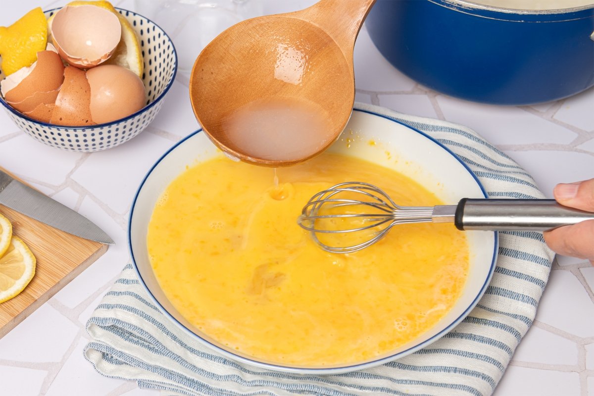Mezclando los huevos con caldo para hacer avgolemono