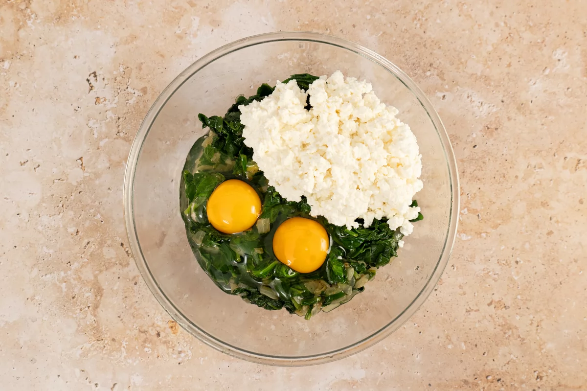 Mezclar el sofrito de espinacas con huevos y queso para la torta pascualina
