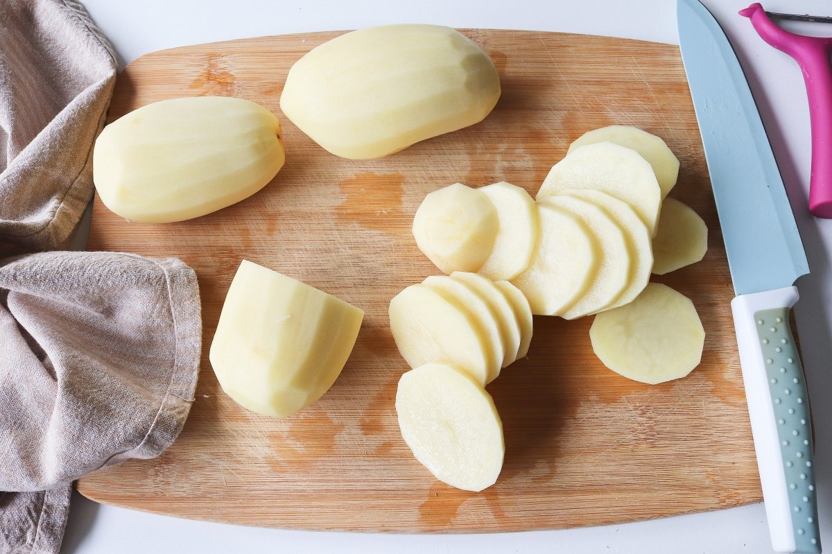 Partir patatas y cebollas para acompañar al pollo al horno