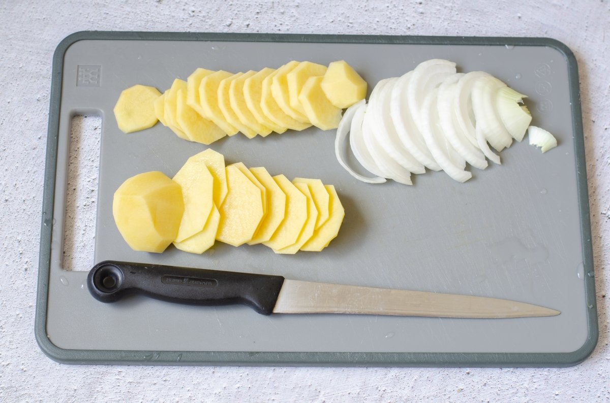 Patatas y cebolla cortadas para hacer dorada a la sidra