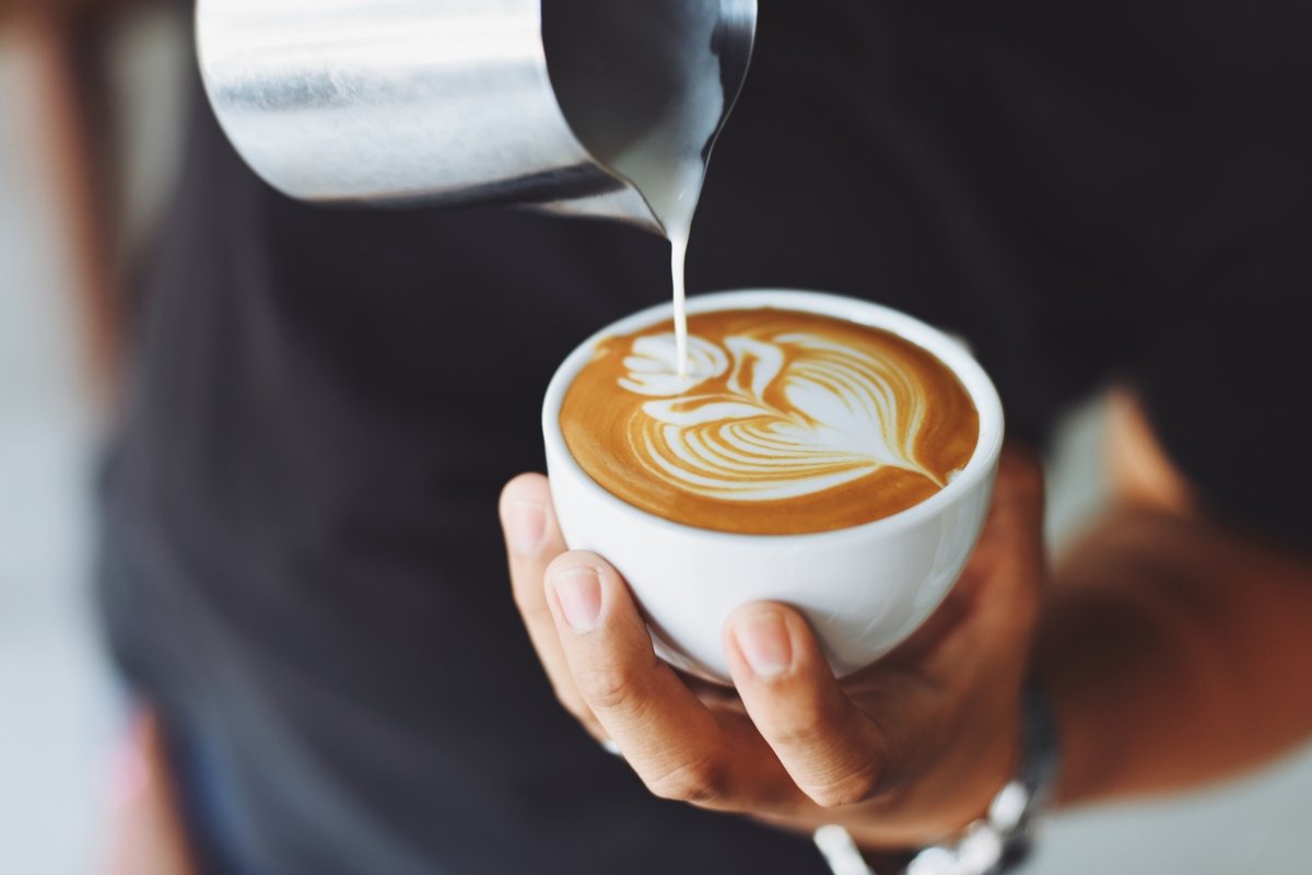 Persona haciendo latte art en un café