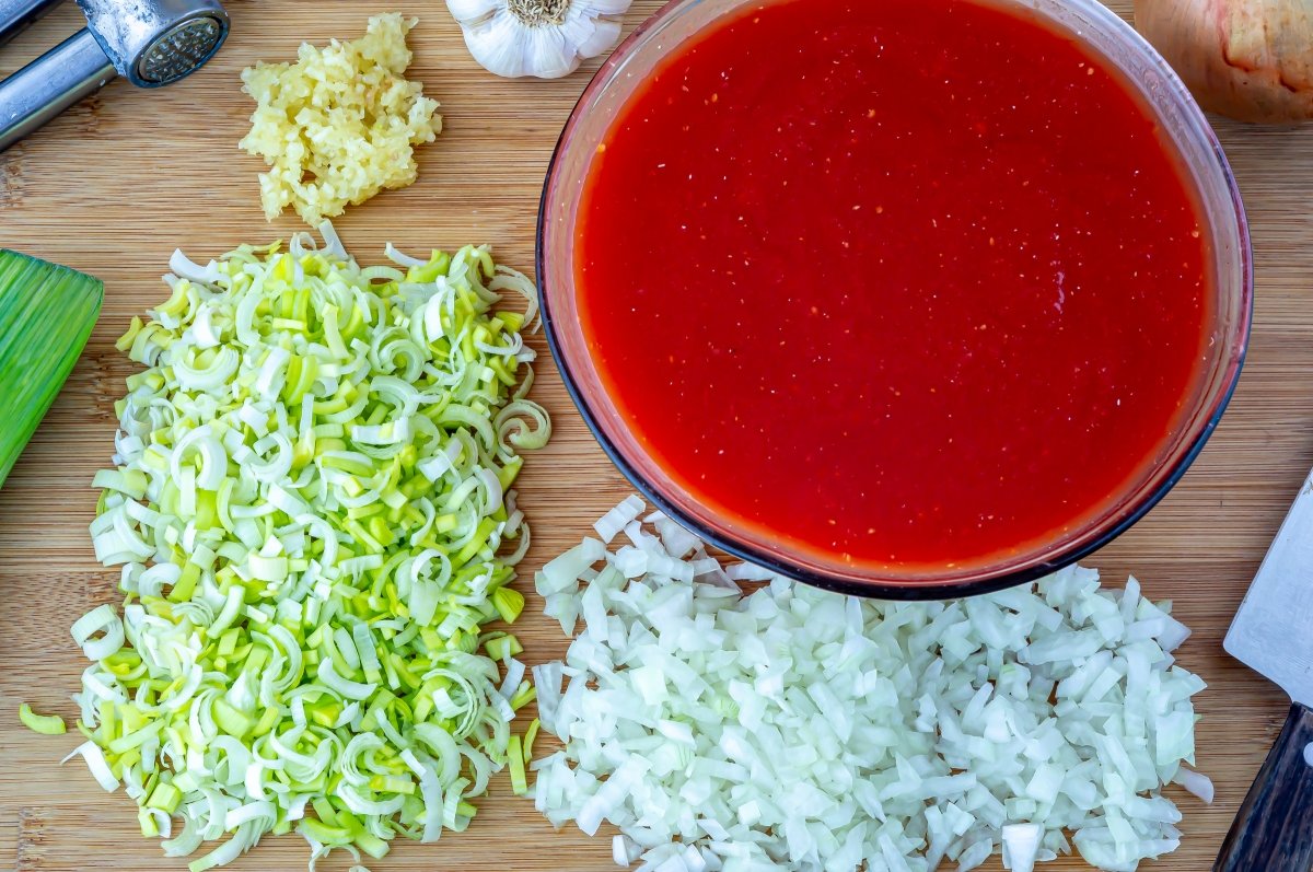 Picar cebolla, puerro y triturar el tomate para la lasaña de verduras