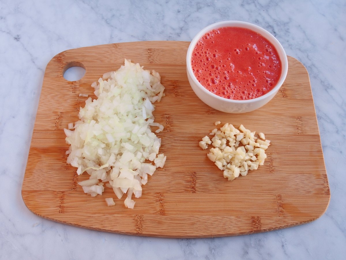 Picar el ajo y la cebolla y triturar el tomate