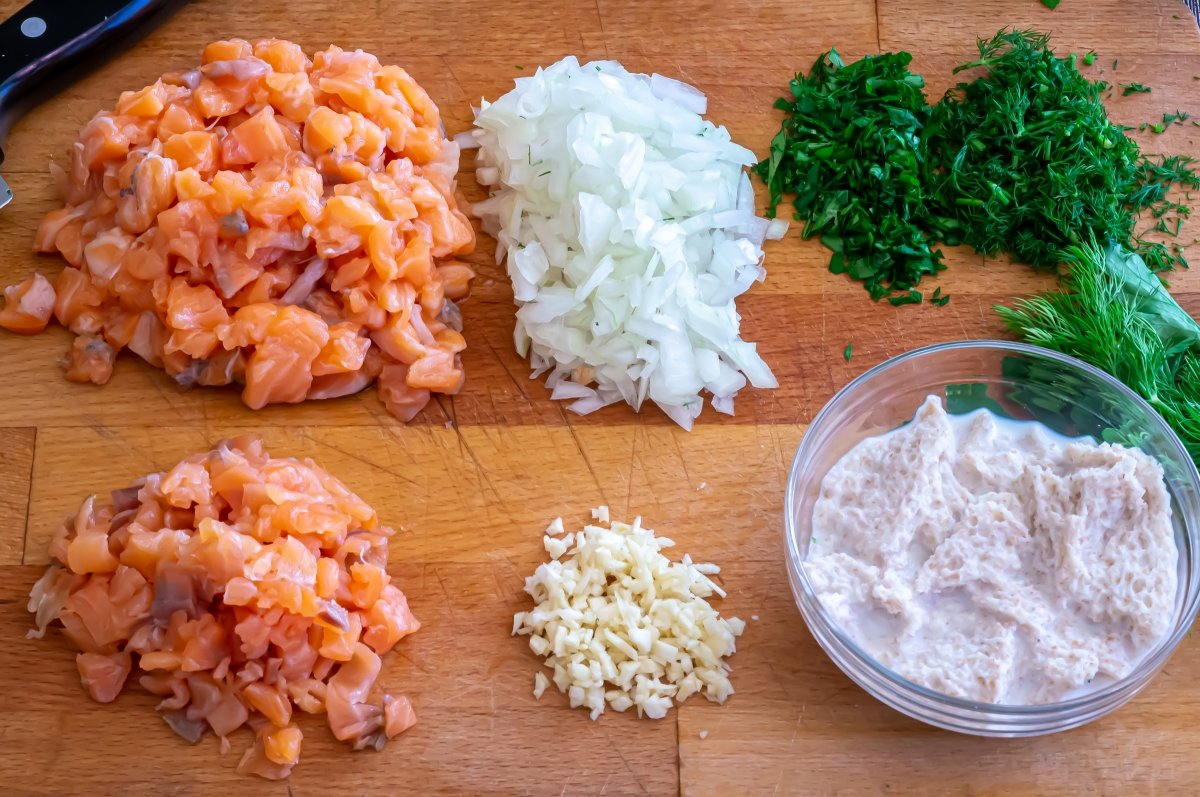 Picar el salmón, la cebolla y el ajo. Remojar el pan
