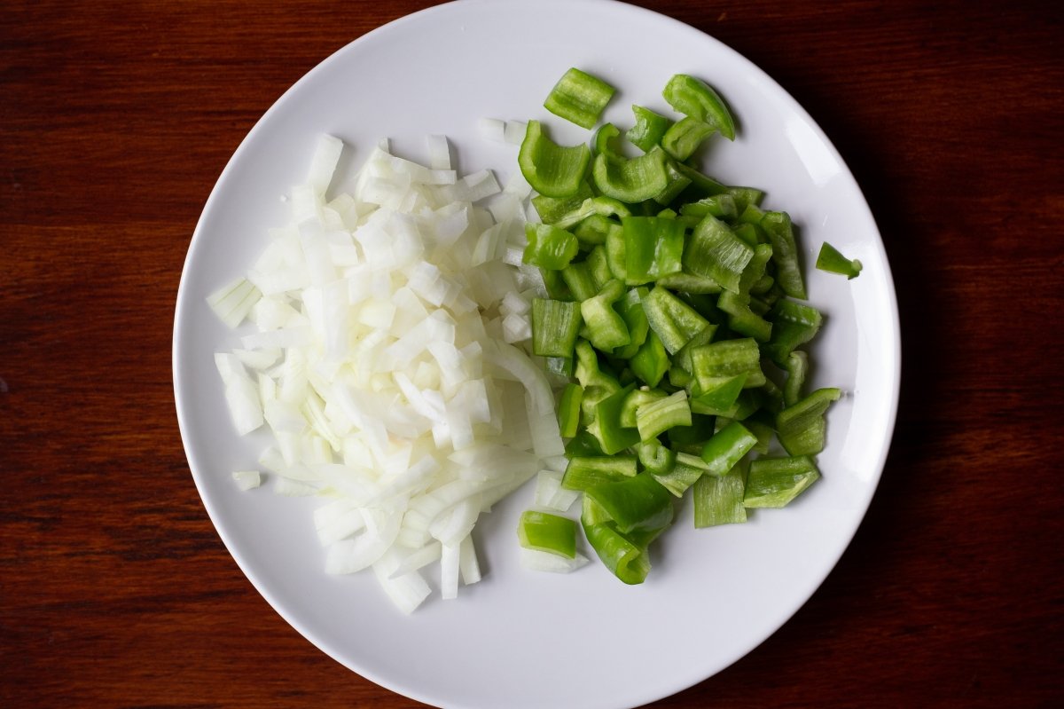 Picar la cebolla y el pimiento y añadirlos al sofrito