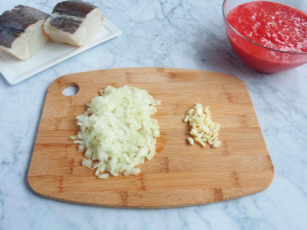 Picar muy fino el ajo y la cebolla para la salsa de tomate del bacalao