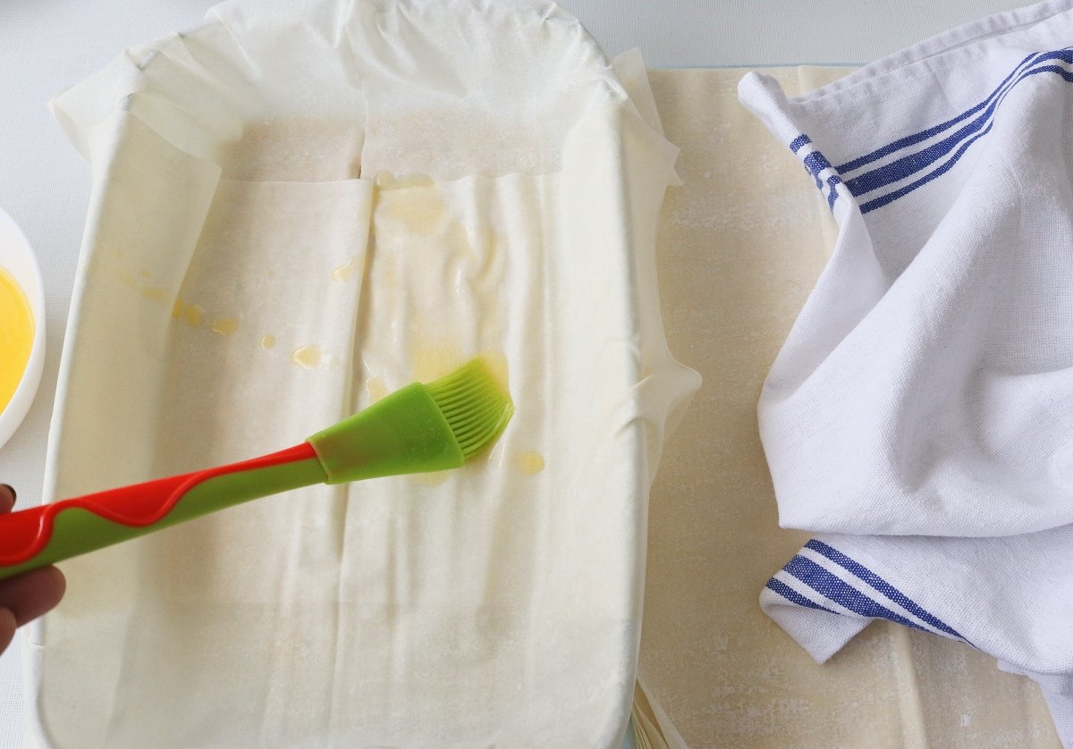 Pincelar con mantequilla las capas de pasta filo para la spanakopita