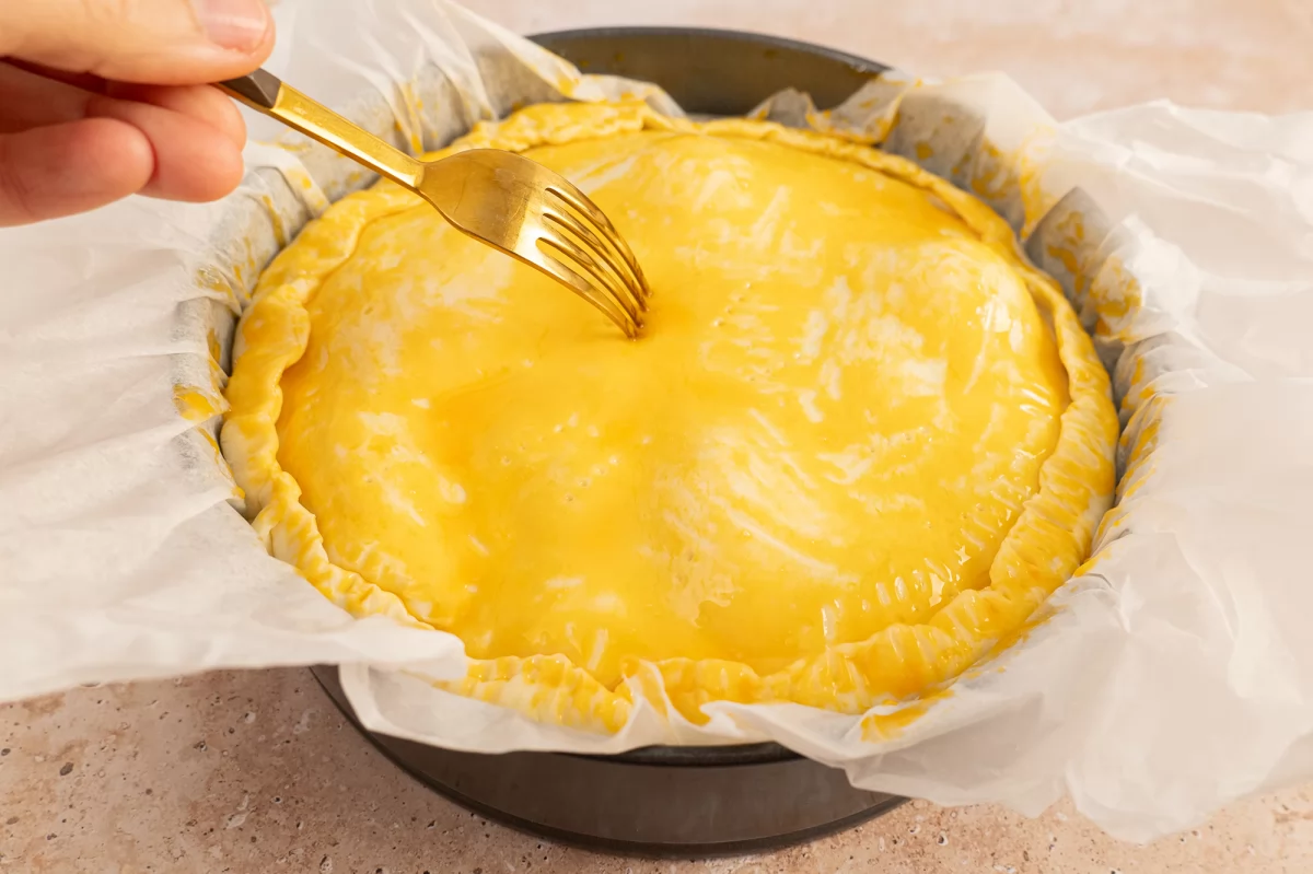 Pinchar la masa brisa superior con un tenedor para la torta pascualina
