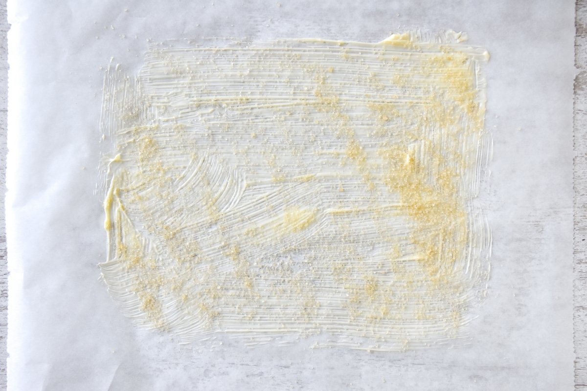 Pintamos el papel de horno con mantequilla y azúcar