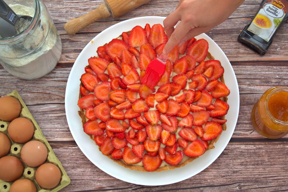 Painting on the strawberry cake with apricot jam
