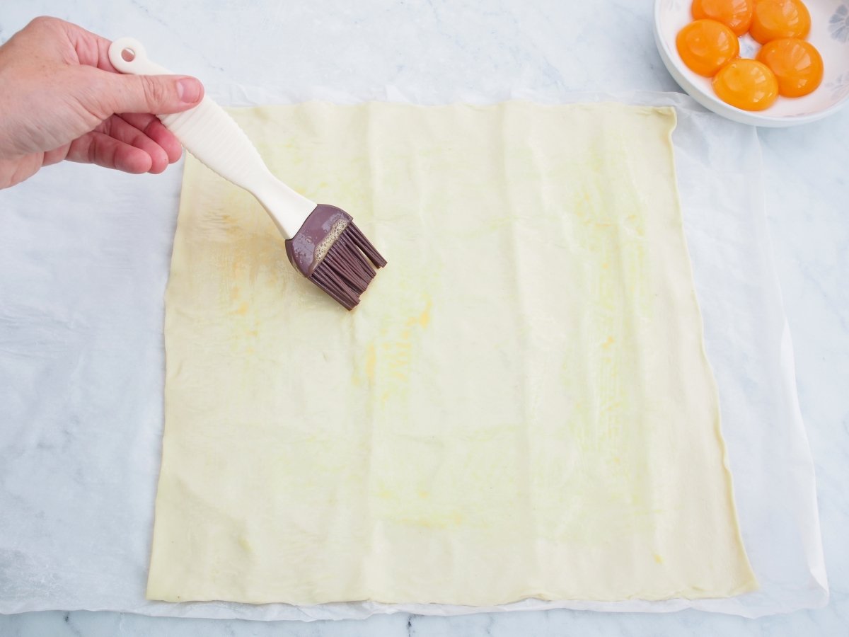 Pintar el hojaldre con huevo para las rosquillas de Alcalá