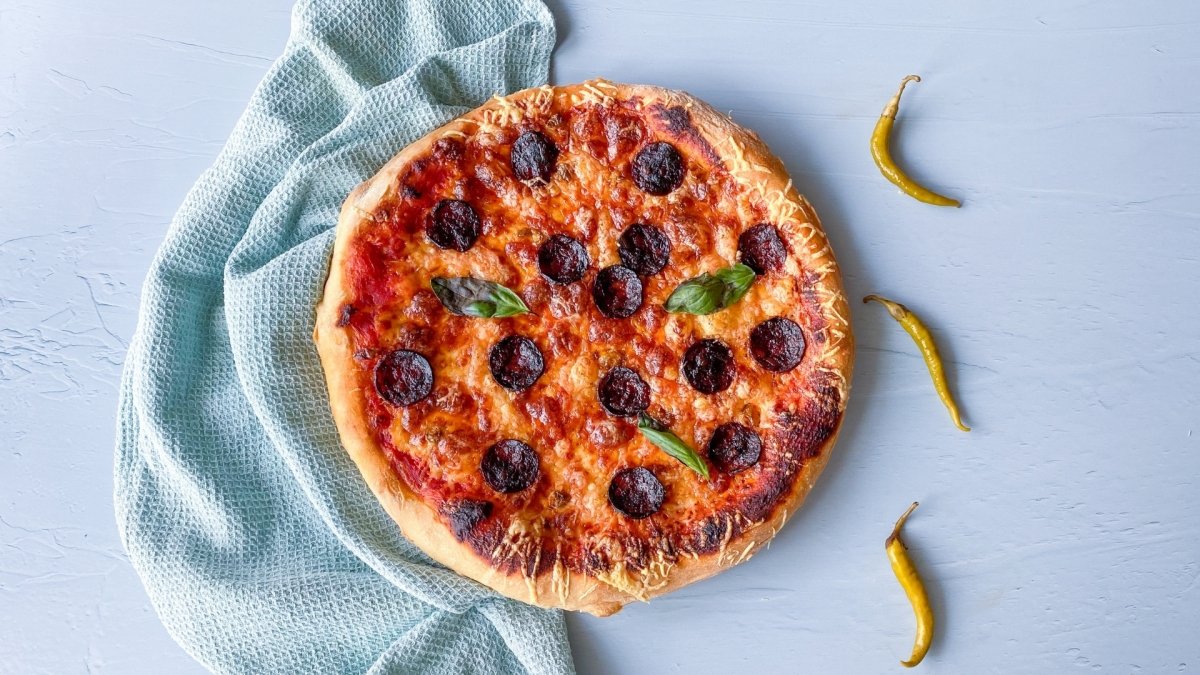 Pizza diávola decorada con albahaca fresca