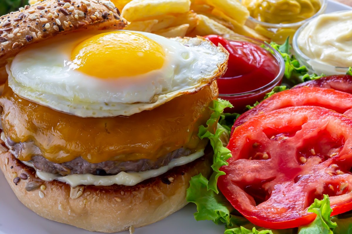 Plato de hamburguesa de carne con huevo, tomate, queso y lechuga